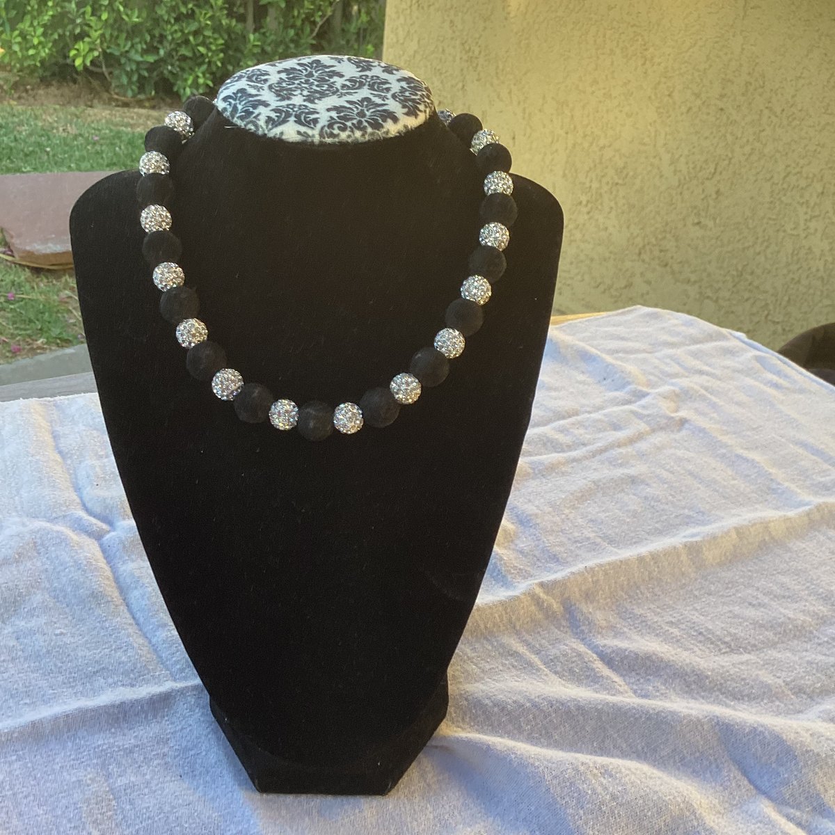 Handmade necklace with a crown charm on a display surface